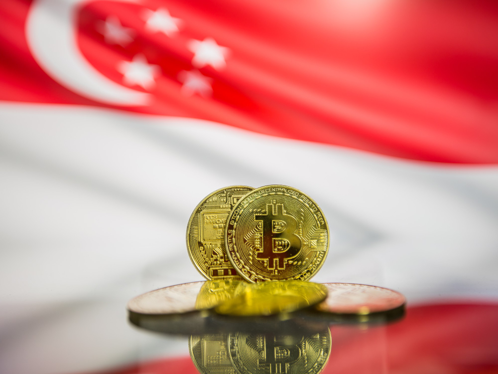 Moedas de Bitcoin em destaque com a bandeira de Singapura ao fundo, simbolizando a entrada da SGX no mercado de contratos perpétuos de criptomoedas.