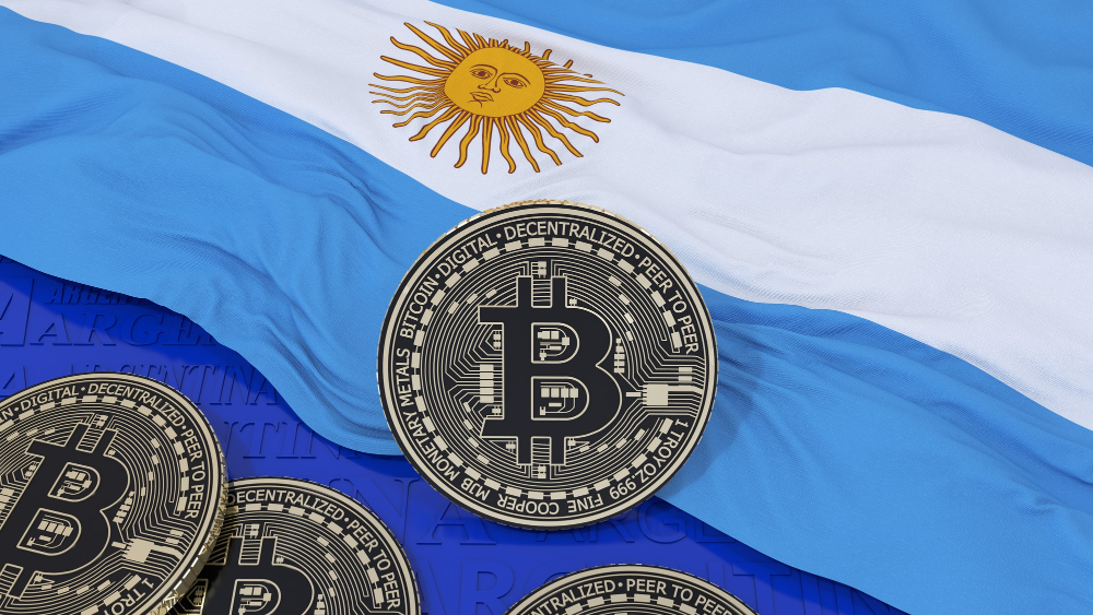 Moedas de Bitcoin sobre a bandeira da Argentina representando a pausa da Coinbase em operações com peso argentino.
